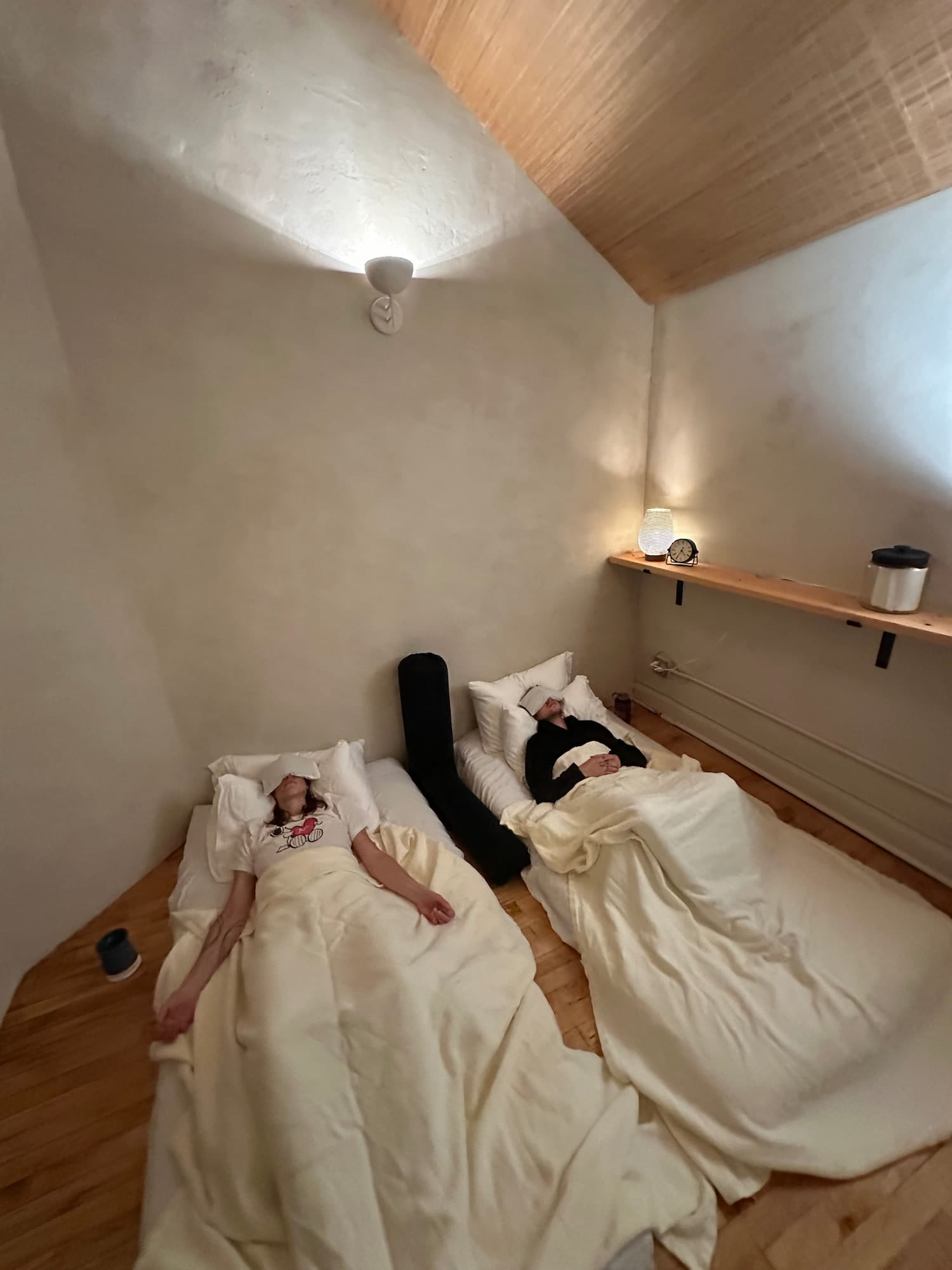 A private sound bath in Duluth, MN. 2 people rest on futons in a relaxing room.
