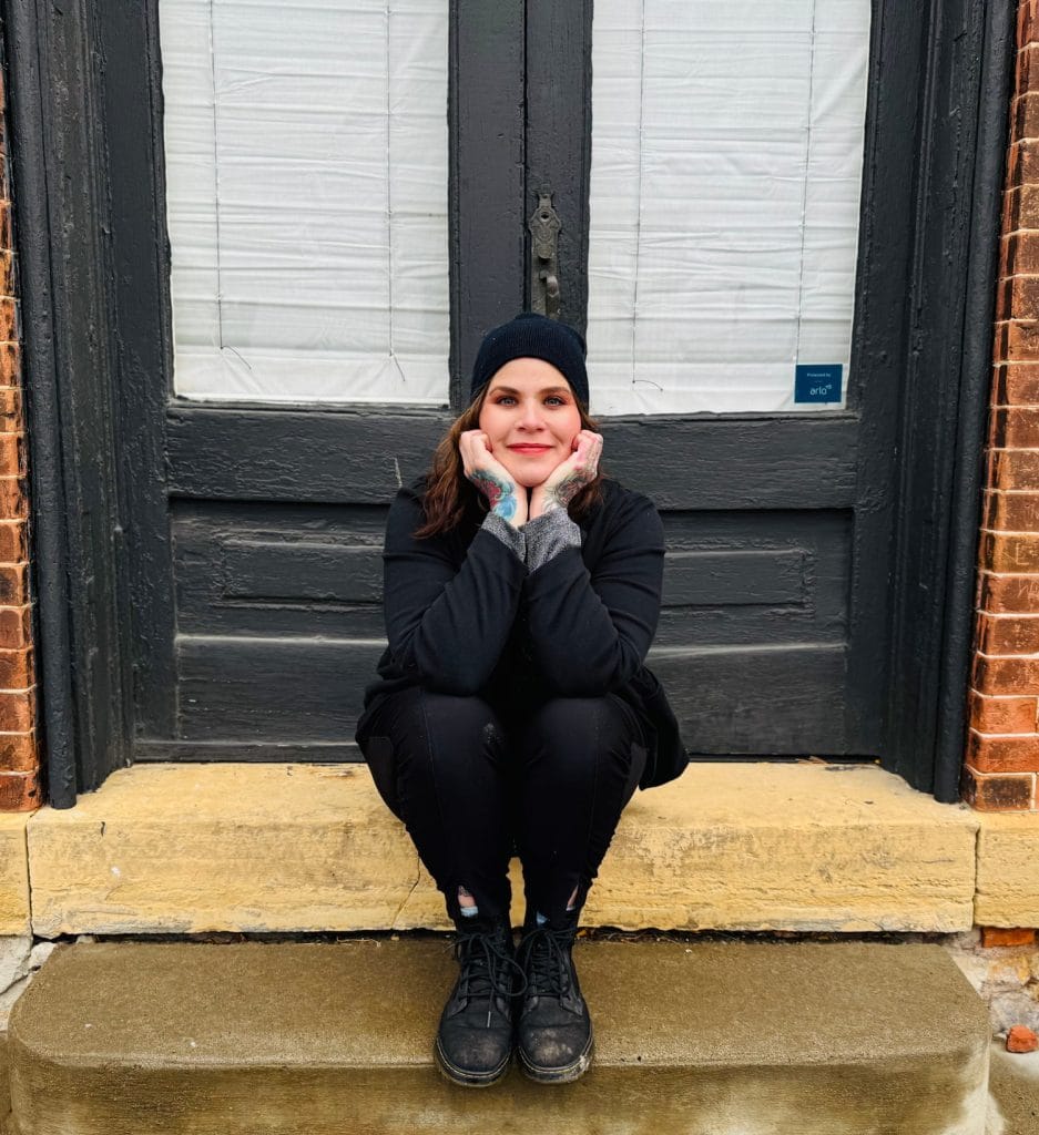 Tracy Murphy sitting on steps in front of doors