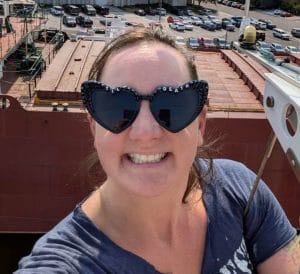 Thai massage therapist Mary Claire (MC) Picard smiling with a ship in the background